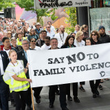 A crowd walks behind the Walk Against Family Violence banner