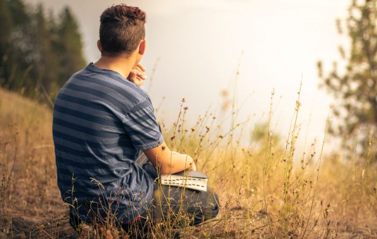 sitting in a field with a book.