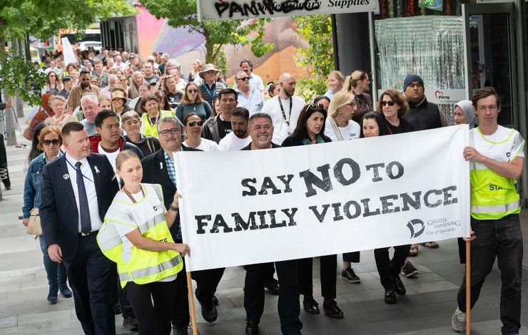 A crowd walks behind the Walk Against Family Violence banner