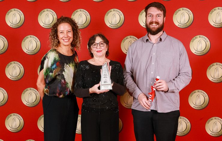 Three people holding an award