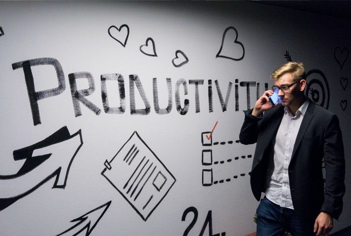 Man walking past a wall with the word Productivity painted on it