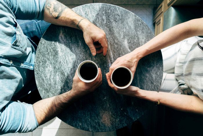 two people sitting at a table with coffee