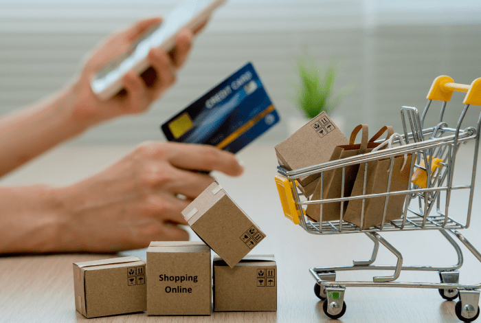 A person holding a credit card and a graphic image of a shopping trolley.