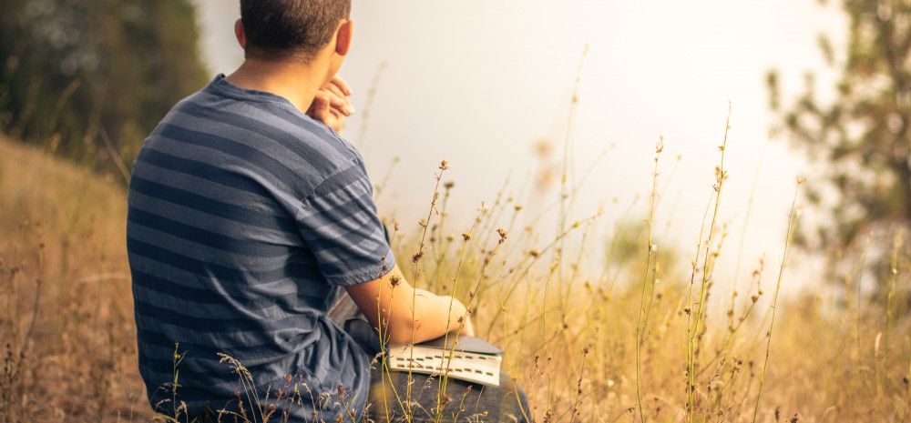 sitting in a field with a book.