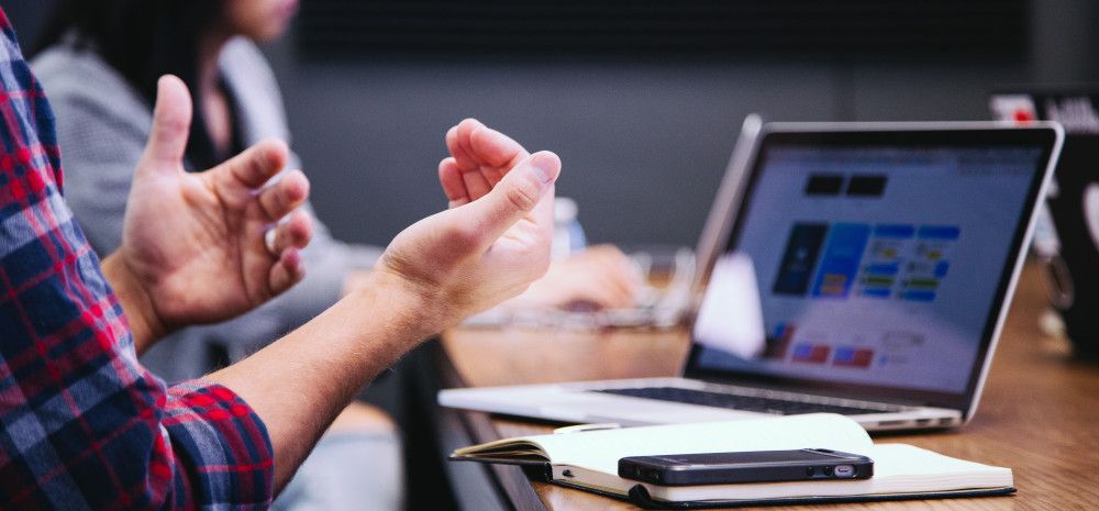 person's hands at desk with laptop