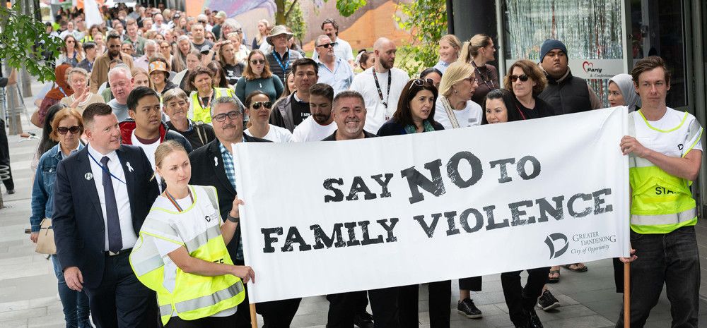 A crowd walks behind the Walk Against Family Violence banner