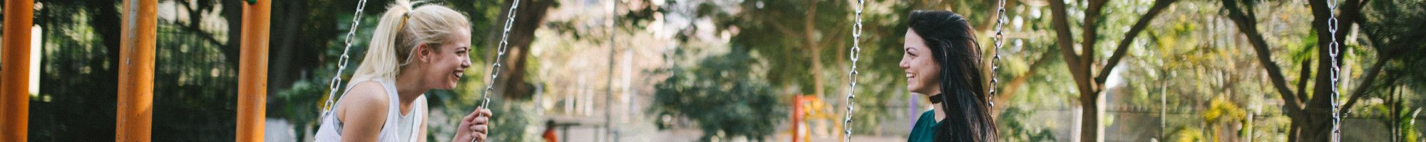 two people sitting on swings