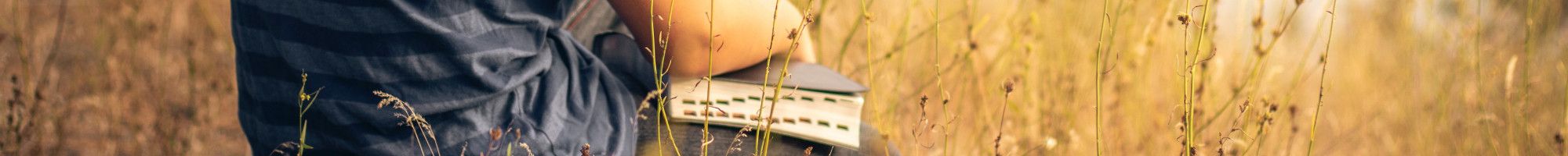 sitting in a field with a book
