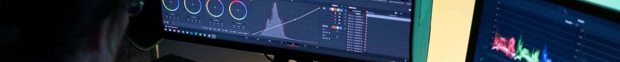 a person sitting in front of two computer screens 