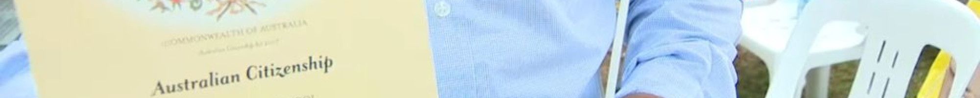 a person holding a Citizenship certificate and an Australian flag