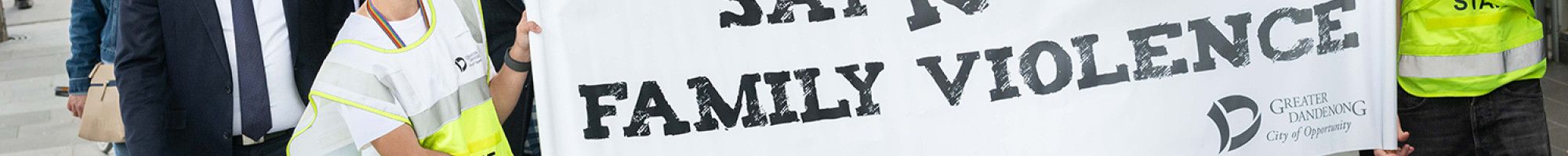 A crowd walks behind the Walk Against Family Violence banner