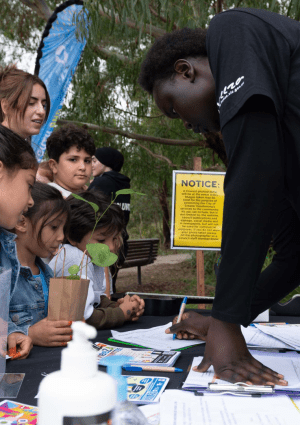 young people chatting to children at a stall at an event